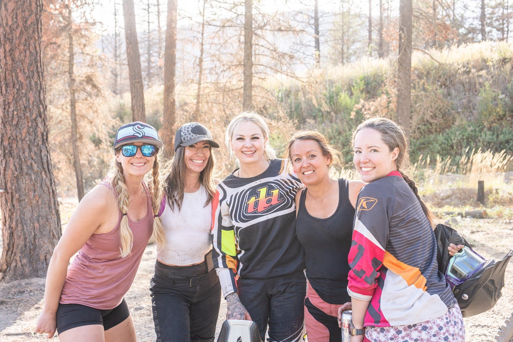 Five Dusthunniez riders smiling together in the forest after a group ride.